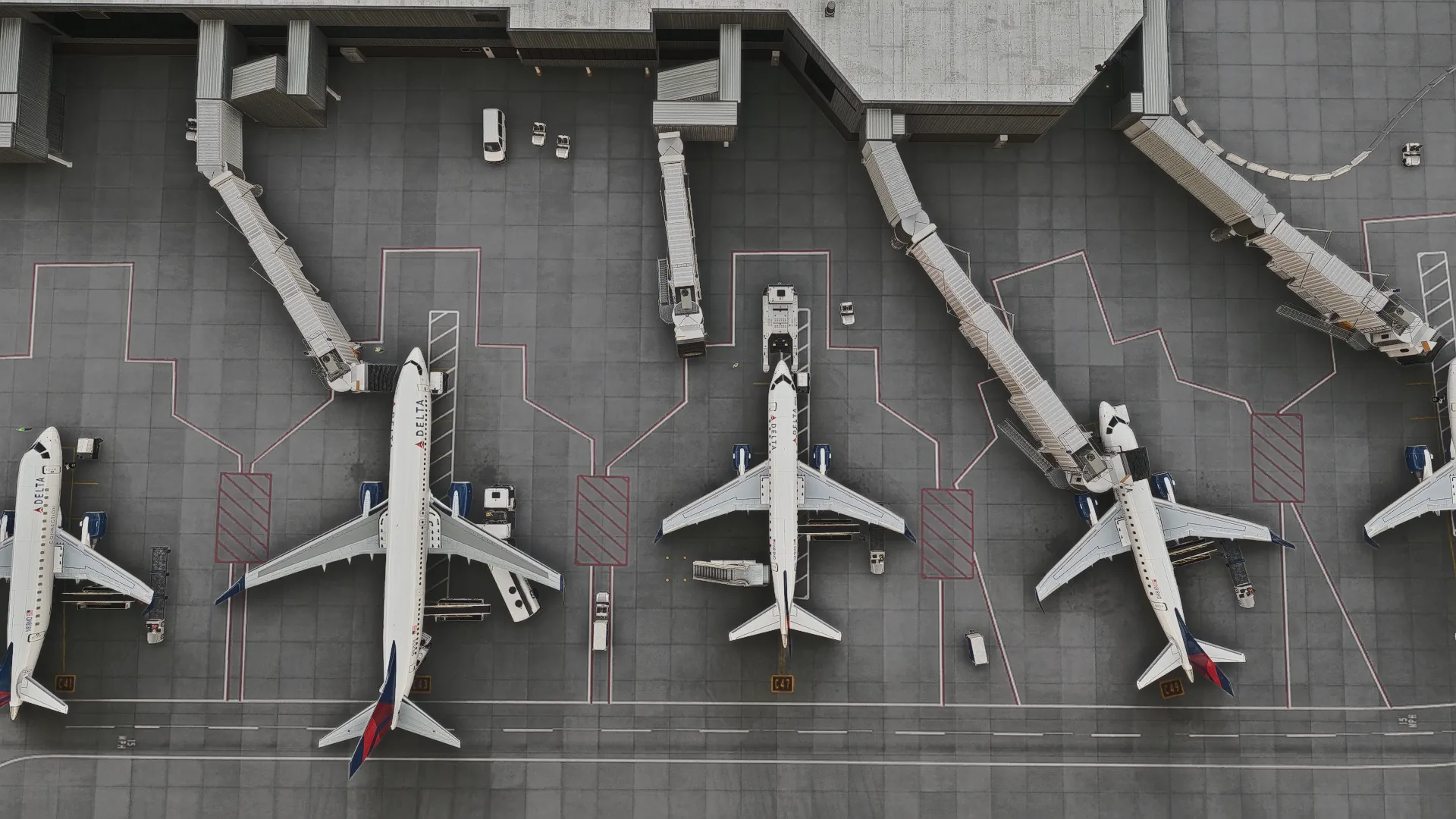 Top-down view of an apron in Microsoft Flight Simulator with AI aircraft at the gates, jet bridges docked and service vehicles around them.