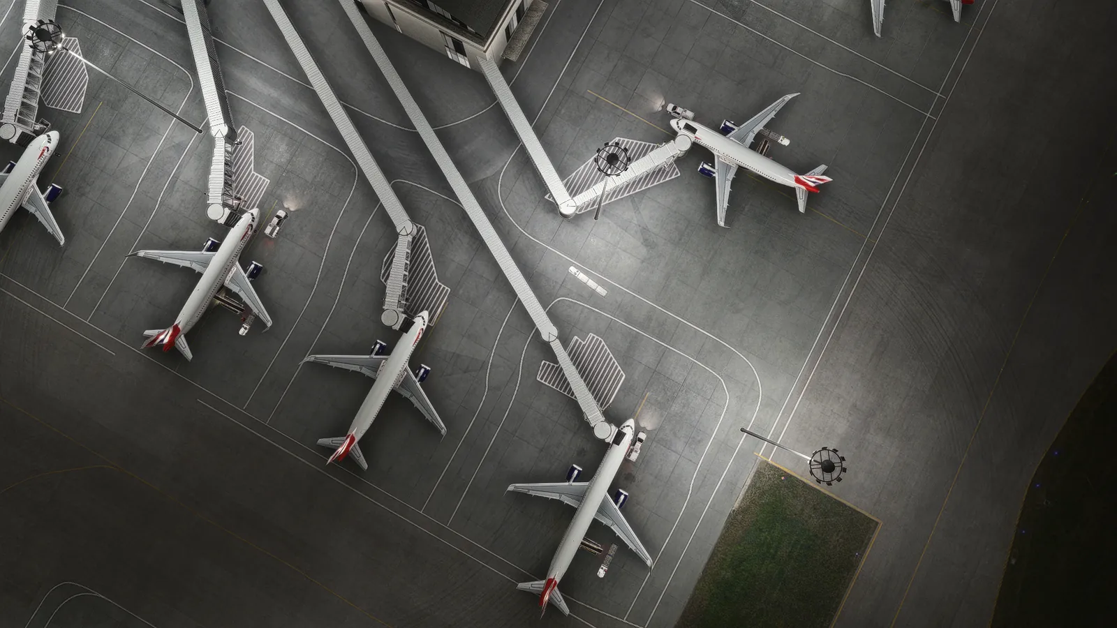 Top-down view at night of A320s at the gates with jet bridges docked.