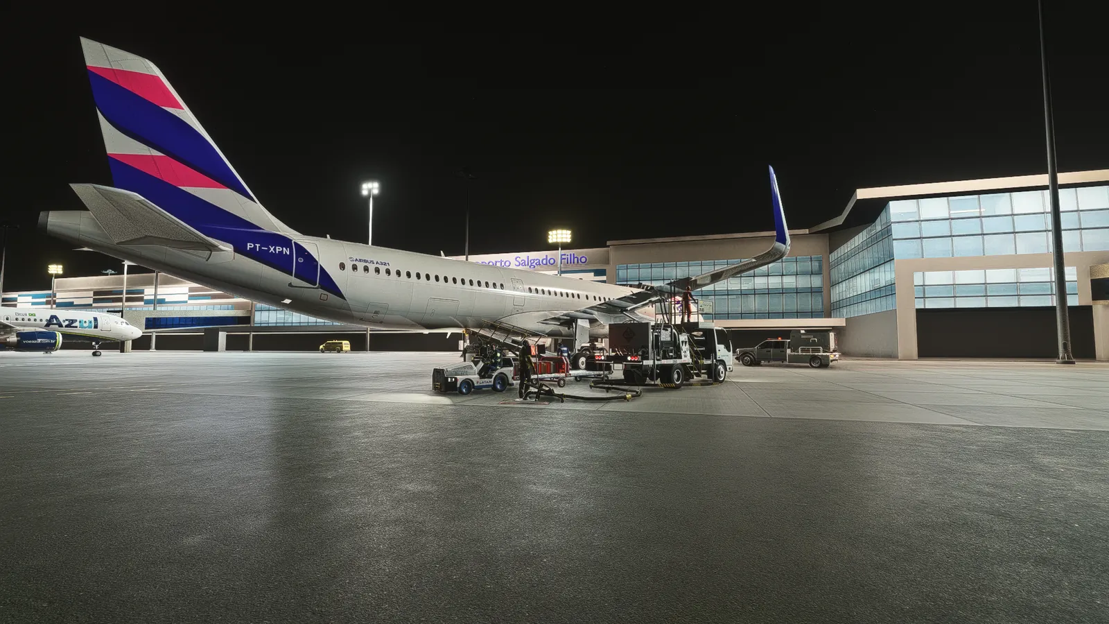 A321 at Porto Alegre at night with a fuel truck, baggage cart and belt loader under the wing.